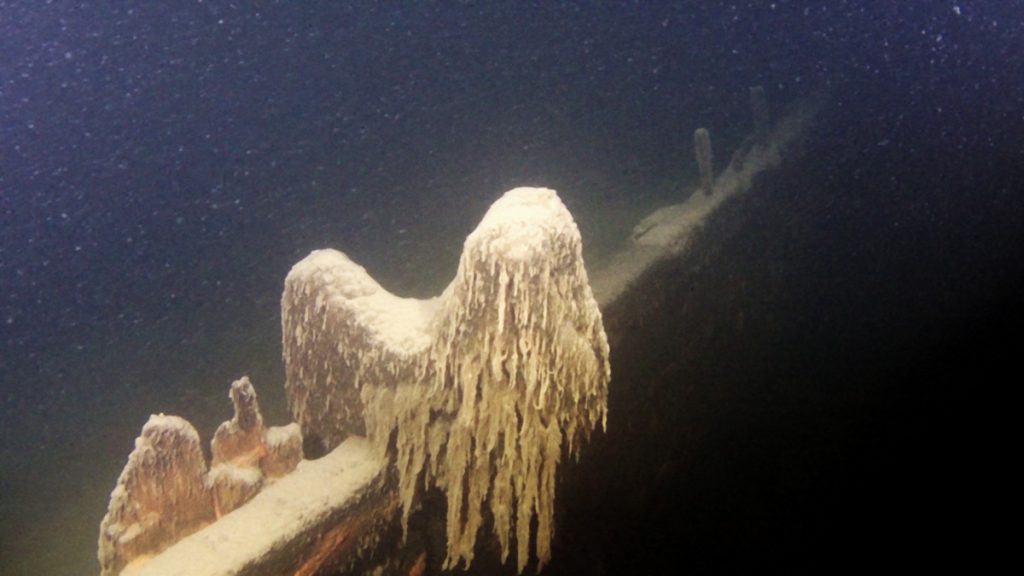 Relitto incrostato nel fondale di un lago, con strutture coperte da concrezioni calcaree visibili durante un’immersione in acqua dolce